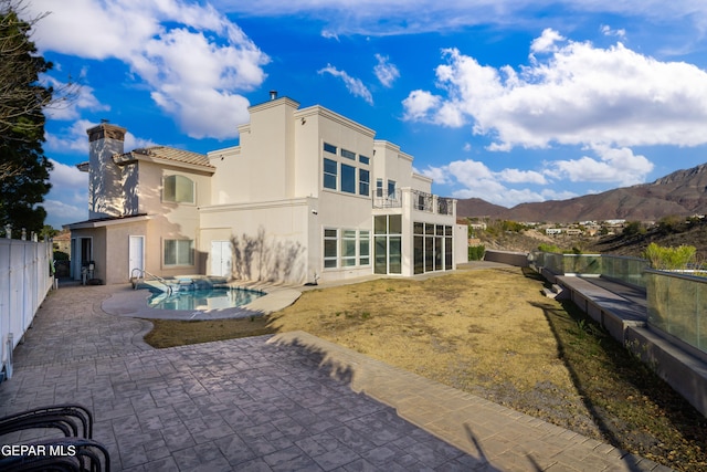 back of house with a fenced in pool, a mountain view, and a patio