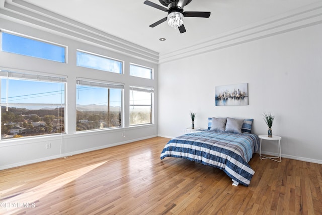 bedroom featuring ceiling fan, hardwood / wood-style floors, and multiple windows