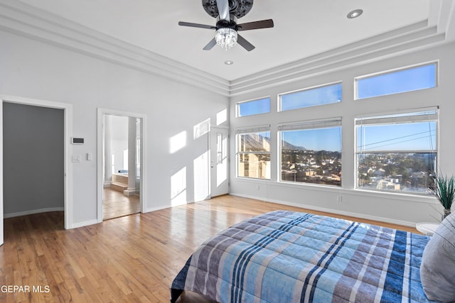 bedroom featuring ensuite bath, ceiling fan, light hardwood / wood-style floors, and multiple windows