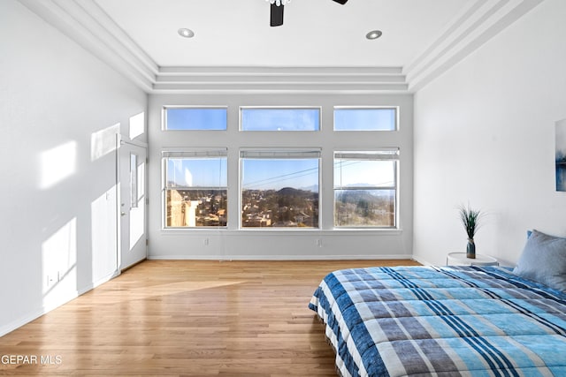 bedroom with ceiling fan, a raised ceiling, and hardwood / wood-style flooring