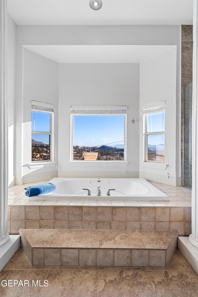 bathroom with tiled tub and a healthy amount of sunlight