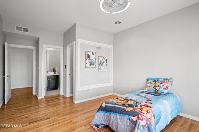 bedroom with ensuite bath and wood-type flooring