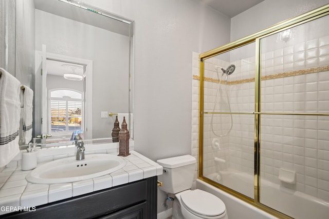 full bathroom featuring toilet, bath / shower combo with glass door, and vanity