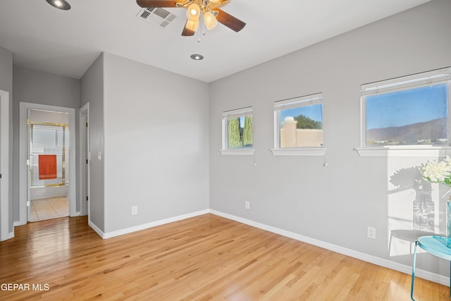 unfurnished bedroom featuring ceiling fan, ensuite bathroom, and light hardwood / wood-style floors