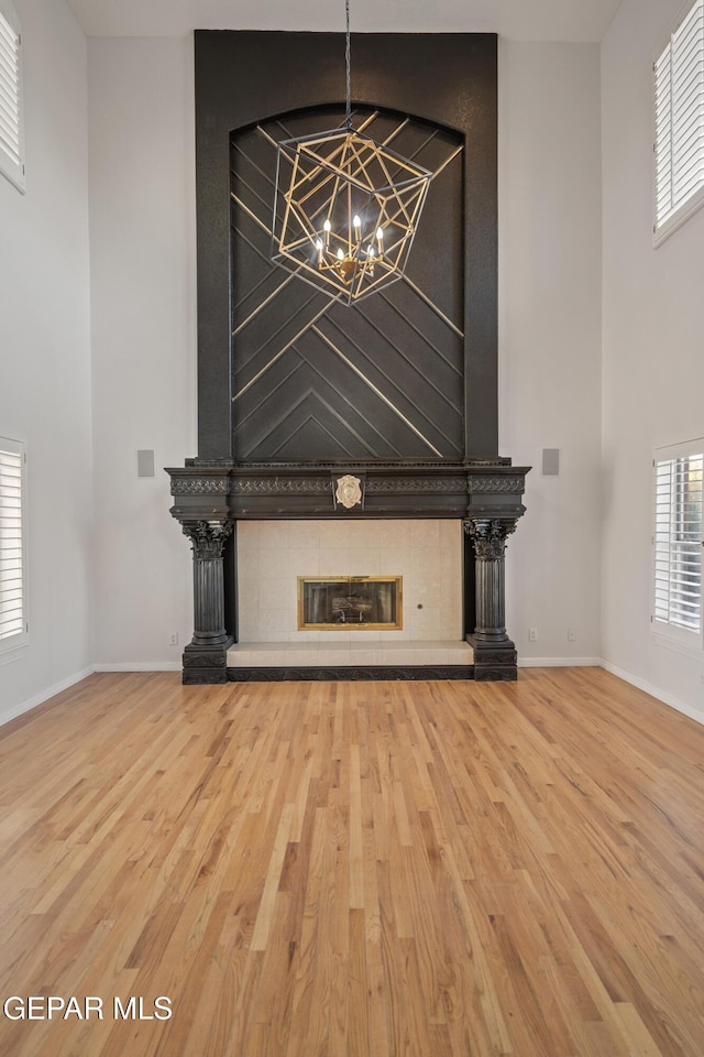 unfurnished living room featuring a notable chandelier, a tile fireplace, and hardwood / wood-style floors