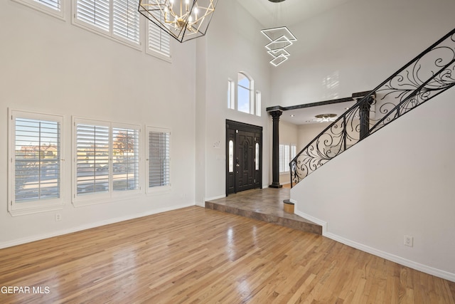 foyer with a notable chandelier, a towering ceiling, and light hardwood / wood-style floors