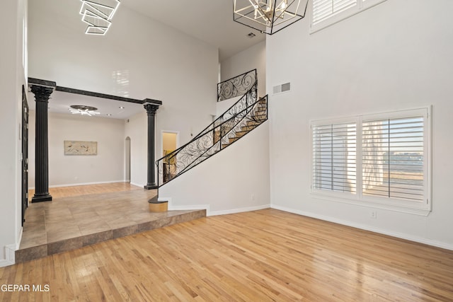 entryway with a high ceiling, wood-type flooring, and an inviting chandelier