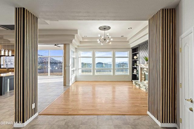 interior space with an inviting chandelier, a mountain view, light tile patterned flooring, a fireplace, and built in shelves