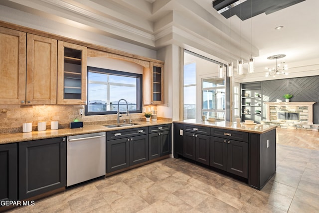 kitchen featuring light stone counters, sink, hanging light fixtures, and dishwasher