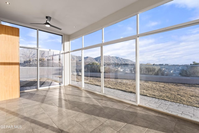 unfurnished sunroom with a mountain view and ceiling fan