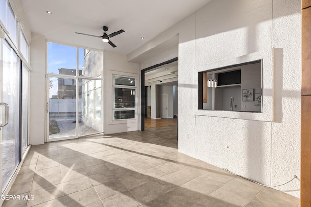 unfurnished living room featuring ceiling fan, expansive windows, and tile patterned flooring