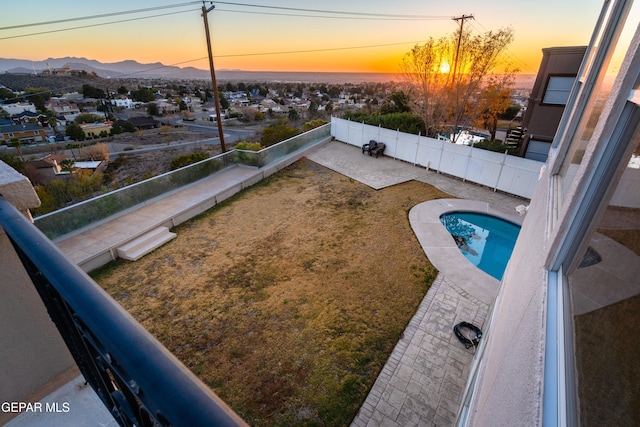 pool at dusk featuring a mountain view and a patio