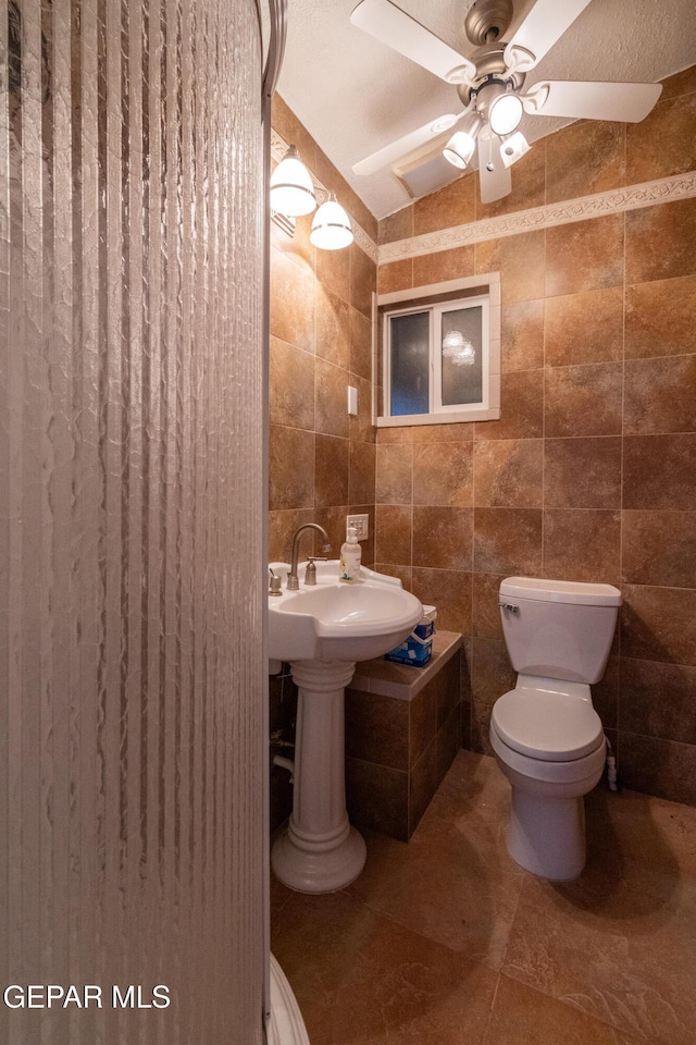 bathroom with ceiling fan, toilet, tile walls, vaulted ceiling, and tile patterned flooring