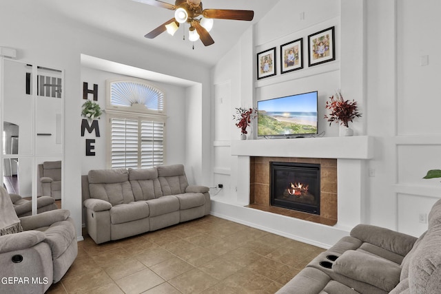 living room featuring ceiling fan, light tile patterned floors, a tiled fireplace, and high vaulted ceiling