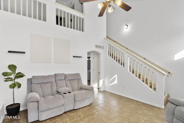 tiled living room featuring ceiling fan and a towering ceiling