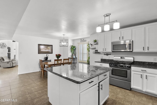 kitchen with white cabinets, appliances with stainless steel finishes, pendant lighting, and a center island