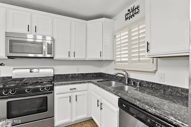 kitchen with sink, dark stone countertops, stainless steel appliances, and white cabinetry