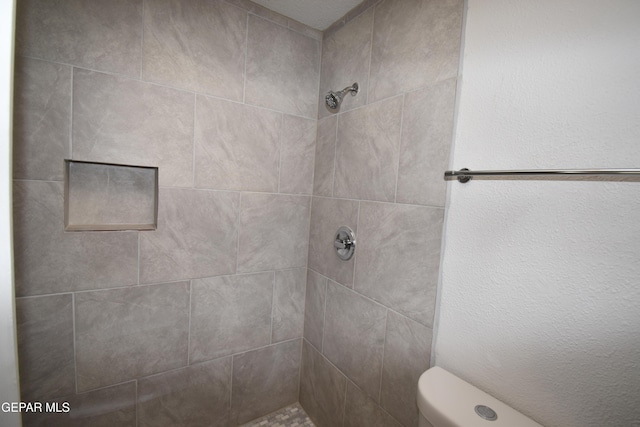 bathroom with toilet and tiled shower