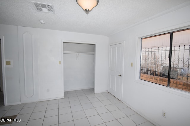 unfurnished bedroom with a textured ceiling, light tile patterned floors, and a closet