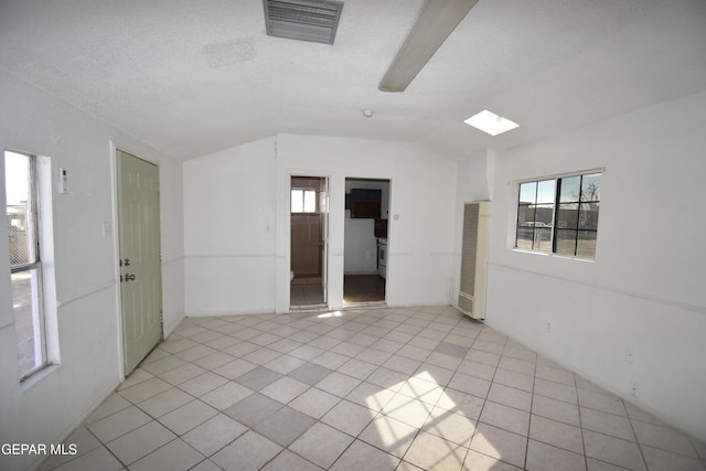 tiled spare room featuring a textured ceiling and lofted ceiling