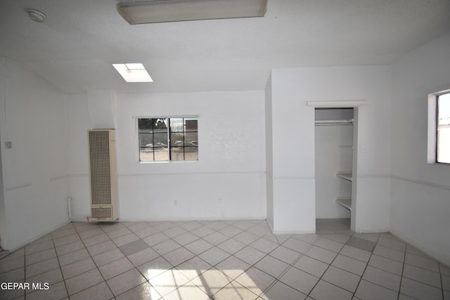 tiled spare room featuring a skylight