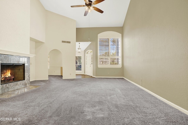 unfurnished living room featuring ceiling fan, carpet, a tile fireplace, and high vaulted ceiling