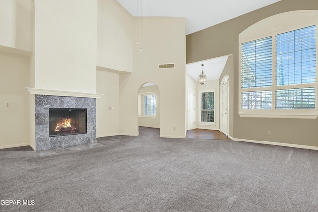 unfurnished living room featuring a high end fireplace, carpet, and high vaulted ceiling