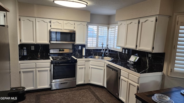 kitchen featuring dark tile patterned flooring, sink, white cabinetry, and appliances with stainless steel finishes