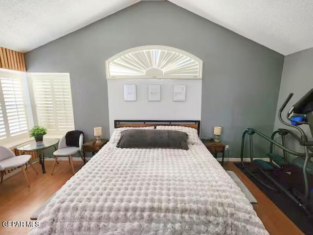 bedroom featuring lofted ceiling, a textured ceiling, and hardwood / wood-style flooring