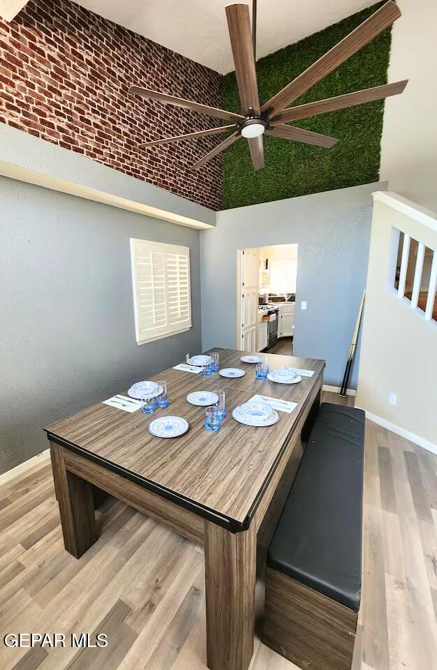 dining space featuring ceiling fan, light wood-type flooring, and vaulted ceiling