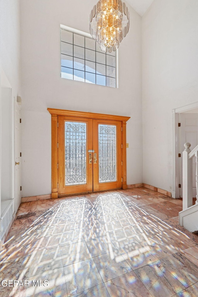 entrance foyer with french doors, a towering ceiling, and a notable chandelier