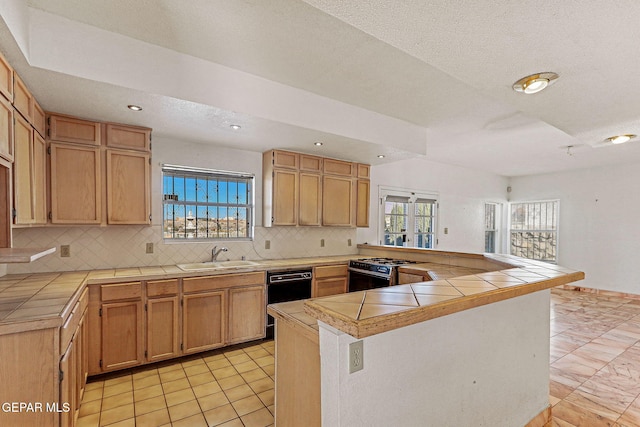 kitchen with kitchen peninsula, tile counters, tasteful backsplash, gas range, and sink