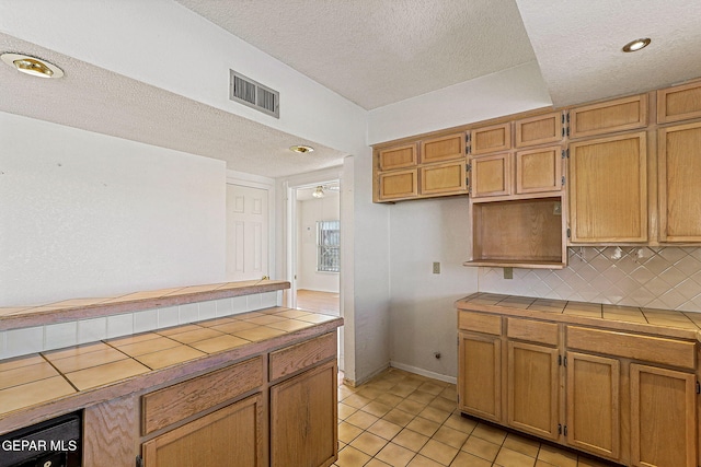 kitchen with tasteful backsplash, ceiling fan, tile countertops, a textured ceiling, and light tile patterned floors