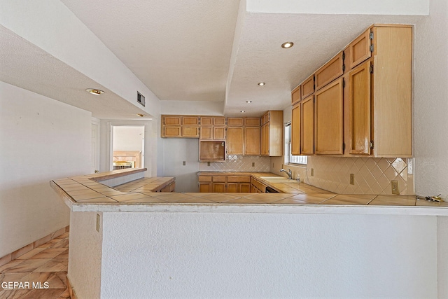 kitchen with sink, backsplash, light tile patterned floors, and kitchen peninsula