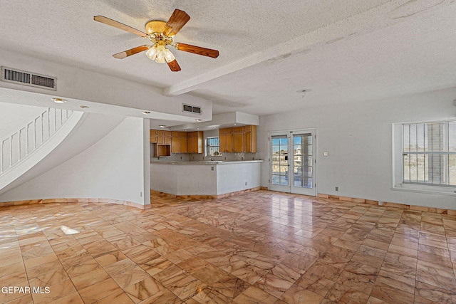 unfurnished living room with ceiling fan, a textured ceiling, beamed ceiling, and french doors