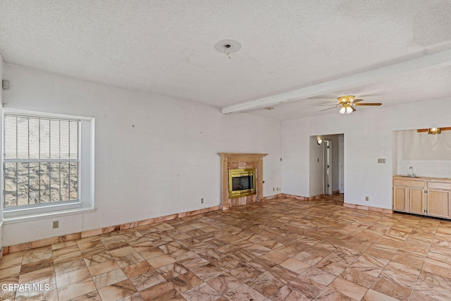 unfurnished living room featuring ceiling fan, sink, a textured ceiling, and beam ceiling