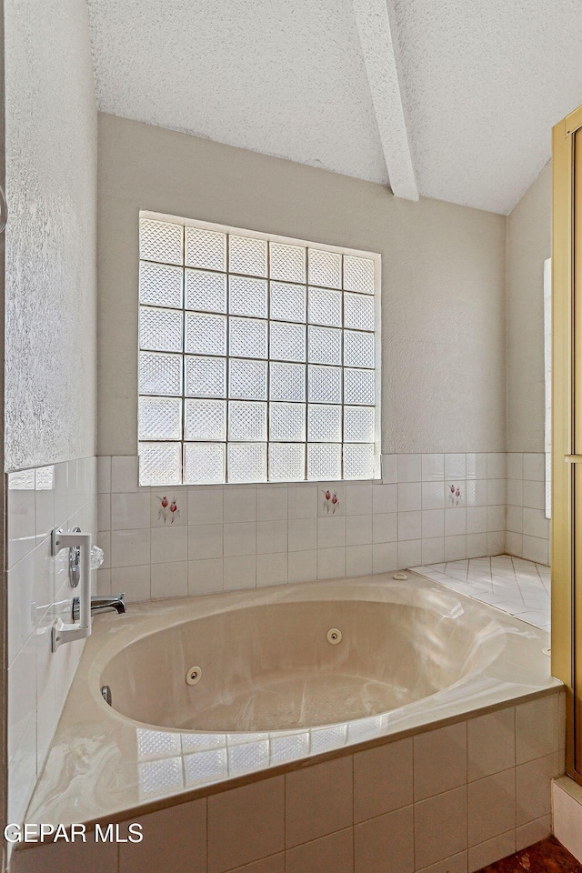 bathroom with a textured ceiling and tiled tub