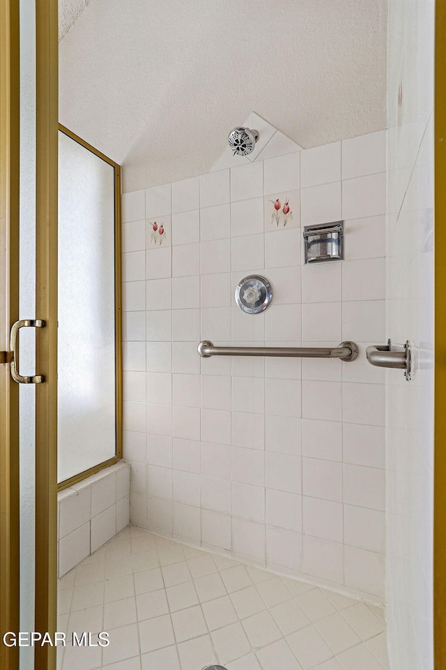 bathroom with a textured ceiling and a tile shower