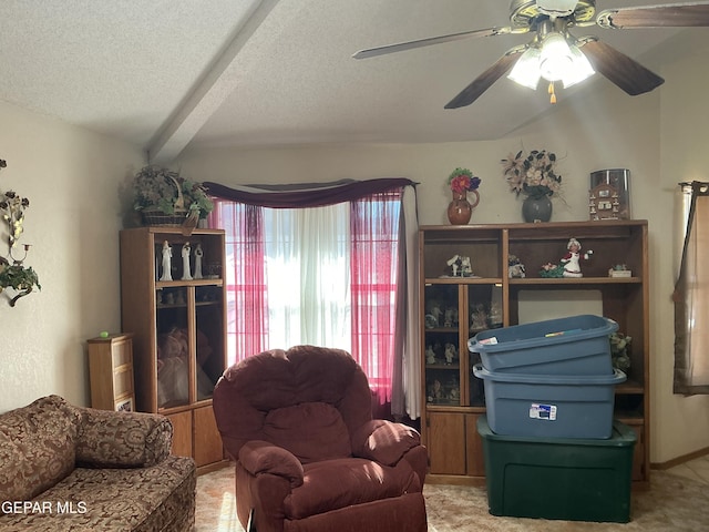 living room with ceiling fan, beam ceiling, carpet floors, and a textured ceiling