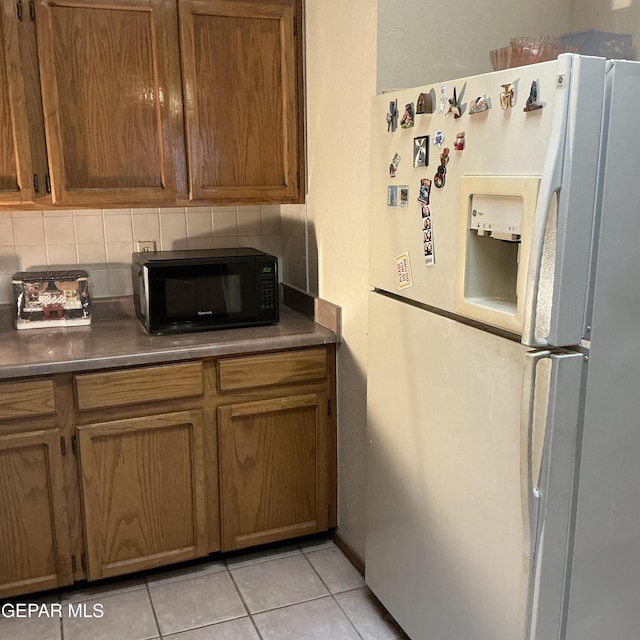 kitchen with backsplash, white refrigerator with ice dispenser, and light tile patterned floors