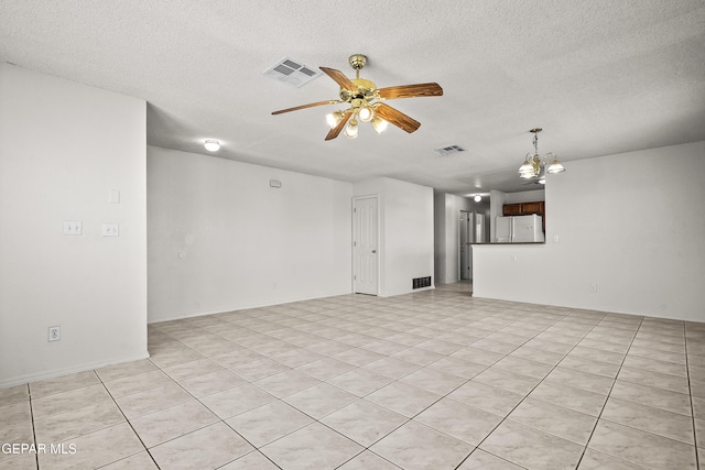 empty room featuring ceiling fan with notable chandelier, a textured ceiling, and light tile patterned flooring