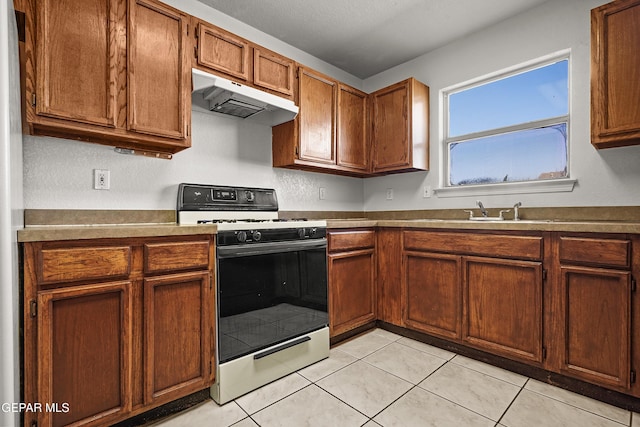 kitchen featuring light tile patterned floors, gas stove, and sink