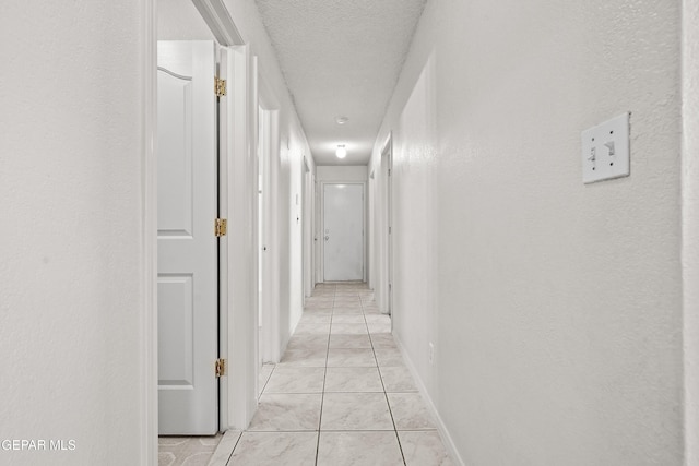 hallway with light tile patterned flooring and a textured ceiling