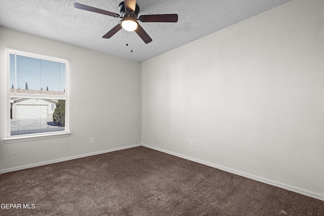 unfurnished room with ceiling fan, dark carpet, and a textured ceiling