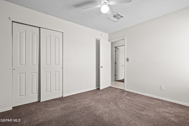 unfurnished bedroom featuring ceiling fan, light colored carpet, a textured ceiling, and a closet