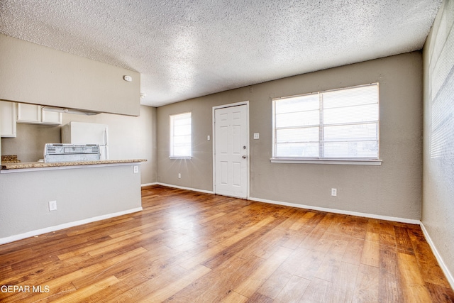 unfurnished living room featuring a textured ceiling and light hardwood / wood-style flooring