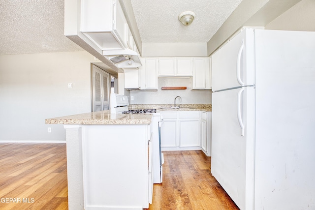 kitchen featuring sink, white appliances, white cabinetry, light hardwood / wood-style flooring, and a textured ceiling