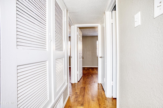 hall featuring a textured ceiling and hardwood / wood-style floors