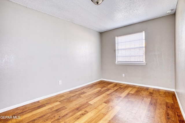 unfurnished room with a textured ceiling and hardwood / wood-style floors