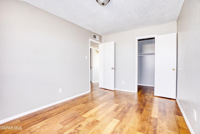 unfurnished bedroom with a textured ceiling, a closet, and light wood-type flooring